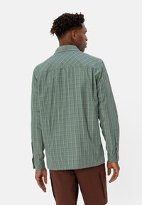 Langsleeve shirt in het groen, met een geruite patroon. Gemaakt van een soepele stof met knopen op de manchetten en een getailleerde kraag.