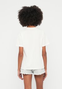 Wit katoenen T-shirt met een losse pasvorm, korte mouwen en een ronde hals. De achterkant heeft een eenvoudig design met minimale stiksel details.