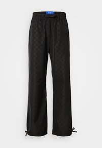 Schwarze Hose mit einem subtilen Sechseckmuster, elastischem Bund mit Kordelzug und verstellbaren Manschetten mit Bändern am Saum.