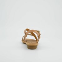 Sandale beige avec des brides croisées, semelle plate et un petit détail de boucle. Texture lisse avec un design minimaliste et ouverture à l'arrière.