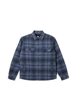 Camisa de franela a cuadros en tonos azul marino y gris, con cierre de botones delanteros, dos bolsillos en el pecho y un diseño de ajuste relajado.