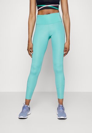 Leggings turquoise clair avec une taille haute, texture lisse et design ajusté, associés à des chaussures de sport grises.