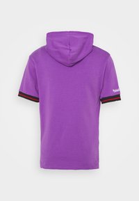 Sweat à capuche violet à manches courtes avec bordures noires et rouges aux poignets, et petit logo blanc sur la manche droite.