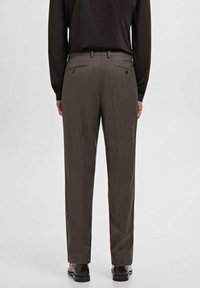 Pantalones marrón a cuadros con un corte entallado, que cuentan con dos bolsillos traseros, una textura de tela suave y detalles sutiles en las costuras.