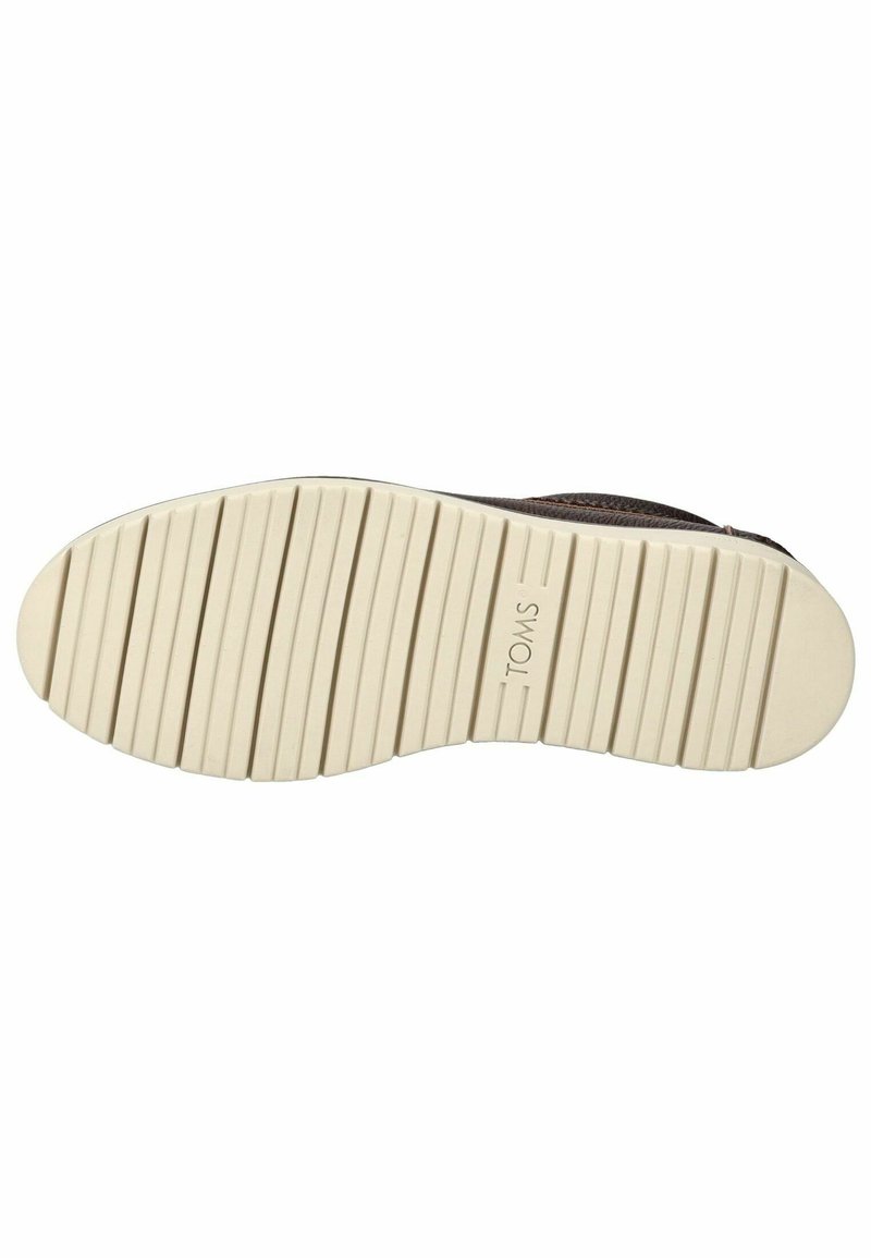 Suela de zapatilla TOMS con un acabado texturizado de goma. Presenta surcos horizontales y un color beige con un logotipo sutil.