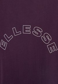 Camiseta marrón con una textura suave que presenta texto en blanco en arco "ELLESSE" en el pecho. Diseño simple sin patrones o acentos adicionales.