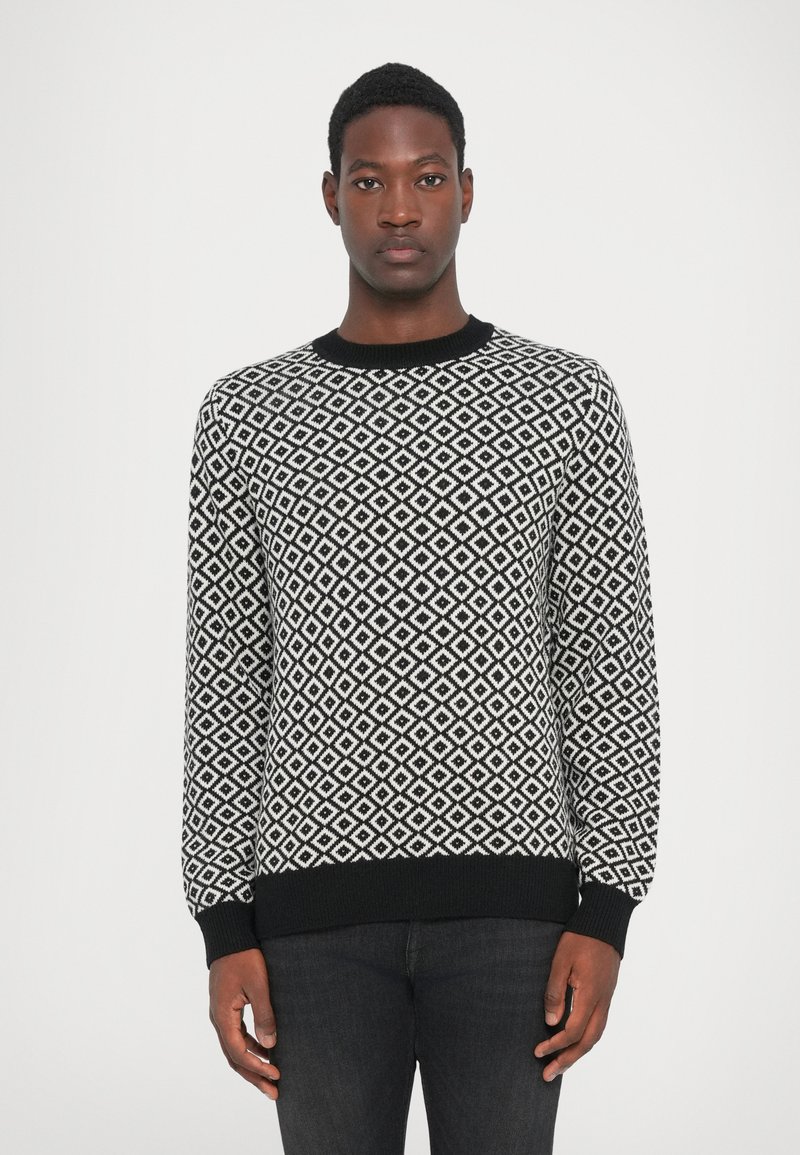 Black and white knitted sweater featuring a diamond pattern, ribbed neckline and cuffs, with a straight cut and long sleeves.