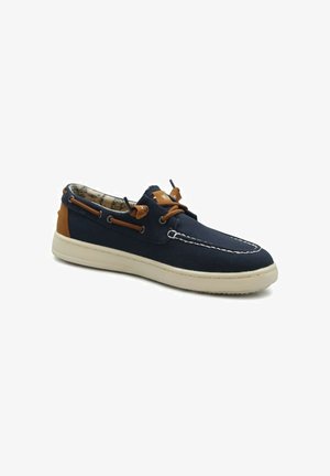 Scarpa da barca blu navy con cuciture bianche, lacci in pelle marrone, rinforzo sul tallone e suola in gomma bianca su sfondo bianco.