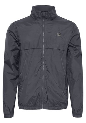 Veste légère pour hommes en gris foncé. Fabriquée en tissu résistant à l'eau, avec un col haut, une fermeture éclair intégrale et des poignets élastiques.