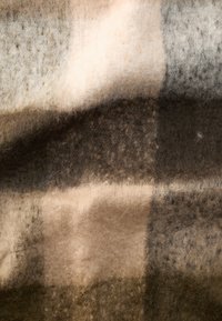 Gyapjú takaró kockás mintával bézs, barna és szürke árnyalatokban, puha, textúrált felülettel és finom színváltozásokkal.