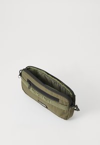 Pungă din material verde măsliniu cu închidere cu fermoar. Dispune de un buzunar frontal cu bandă textilă și un interior moale căptușit. Formă rectangulară.
