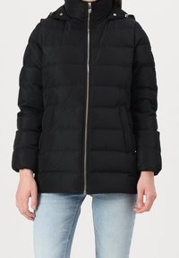 Zwarte gewatteerde jas met een hoge kraag, ritssluiting aan de voorzijde en geribbelde manchetten. Heeft een horizontaal doorgestikt patroon en zijzakken.