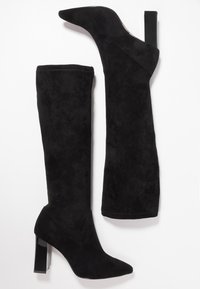 Bottes montantes en daim noir avec un bout pointu et un talon carré épais et transparent. Présentent une texture lisse et des coutures nettes.
