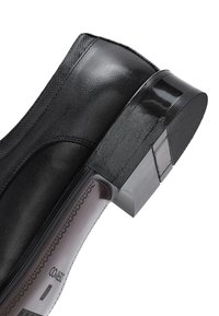 Zwarte leren enkellaars met gestructureerde hak en zool, zichtbare stiksels en merknaam gedrukt op de binnenzool.