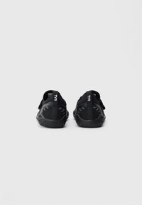Pair of black water shoes with textured soles viewed from the back, featuring a TYR logo on pull tabs against a white background.
