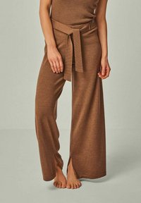 Braune weit geschnittene Hosen mit gestrickter Textur, hoher Taille und einem passenden Gürtel, der vorne gebunden ist. Enthält seitliche Schlitze für zusätzliche Details.