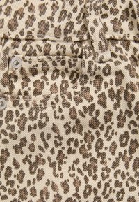 Tessuto leopardato con tonalità beige e marrone, caratterizzato da una superficie testurizzata e cuciture visibili. Include un dettaglio con bottone a pressione in metallo.
