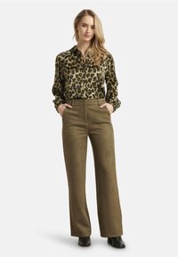 Leopard print blouse with button front, long sleeves, and olive green wide-leg pants. Fabric has a smooth texture; shoes are black.