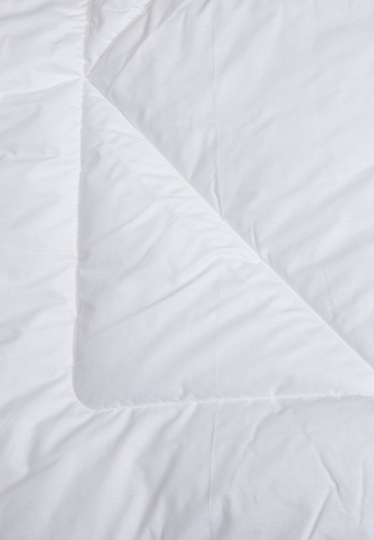 Weißer Bettbezug aus glattem, strukturiertem Stoff mit einem gesteppten Design und diagonaler Nahtmusterung. Die Kanten haben einen sauberen, genähten Abschluss.