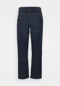 Vaqueros azul oscuro de corte recto vistos desde atrás, con dos bolsillos traseros y detalles sutilmente desgastados en los bordes de los bolsillos.