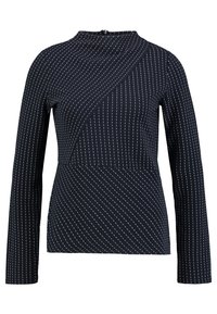 Marinblå långärmad topp med en unik diagonal paneldesign. Tyget har ett subtilt randigt mönster med ljusa linjer.