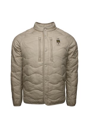 Giacca trapuntata beige con colletto rialzato, chiusura anteriore a scatti e due tasche con zip, realizzata in materiale leggero e testurizzato.