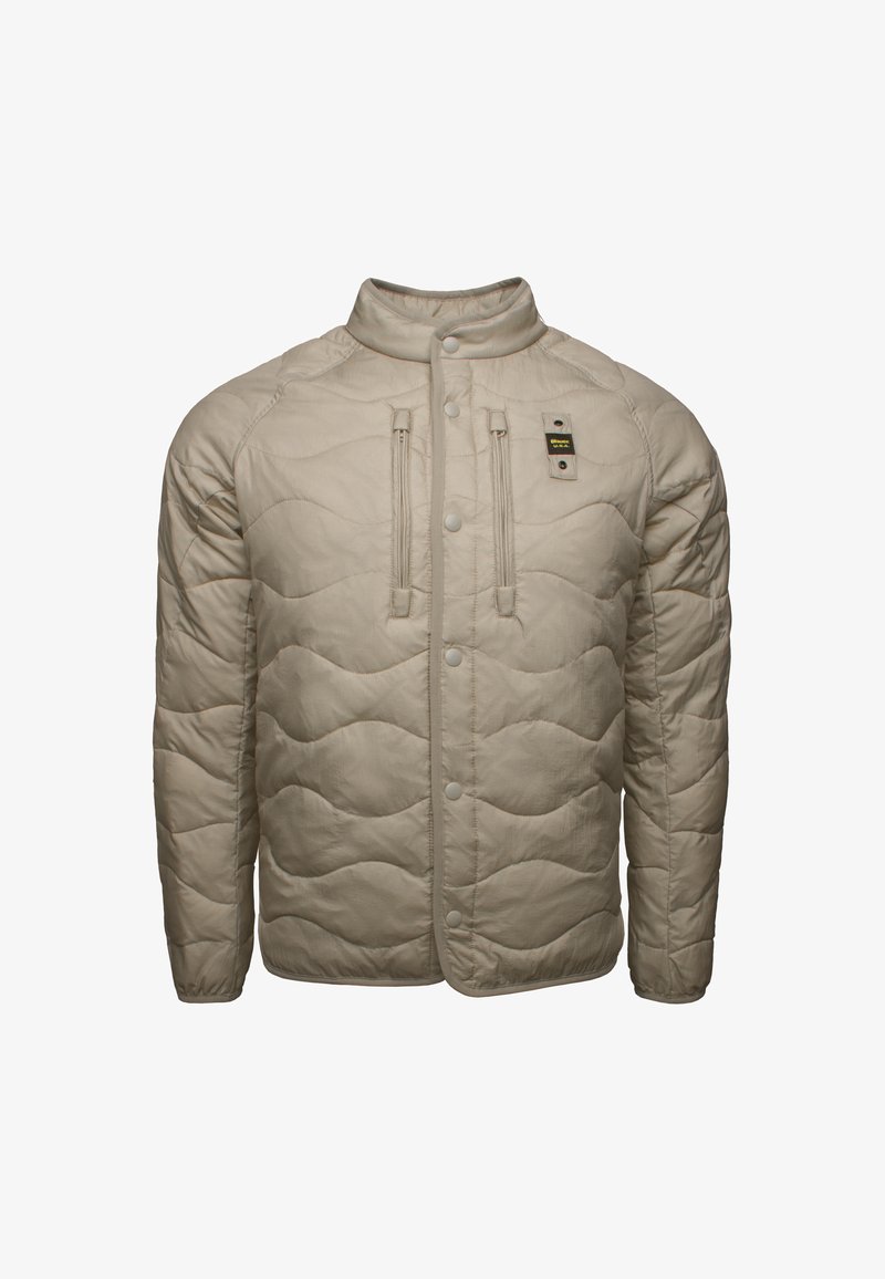 Giacca trapuntata beige con colletto rialzato, chiusura anteriore a scatti e due tasche con zip, realizzata in materiale leggero e testurizzato.