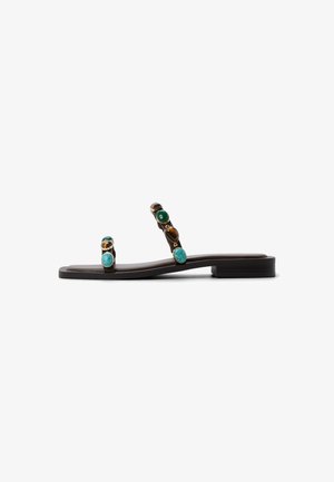 Flat sandal with a brown base, featuring decorative stones in green and turquoise, minimal straps, and a low-profile heel.