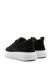 Sneakers in pelle nera con suola bianca, caratterizzati da dettagli dorati e un logo sul tallone. Design classico con una texture liscia.