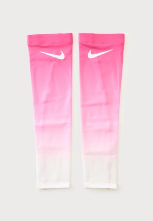 Pár růžovo-bílých rukávů Nike s bílými logy swoosh blízko vrchu, položených naplocho na bílém pozadí.