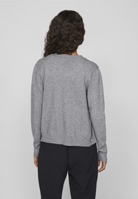 Grå stickad tröja med rund halsringning, ribbad mudd och fåll, samt en avslappnad passform. Strukturen är mjuk och slät, utan synliga mönster.