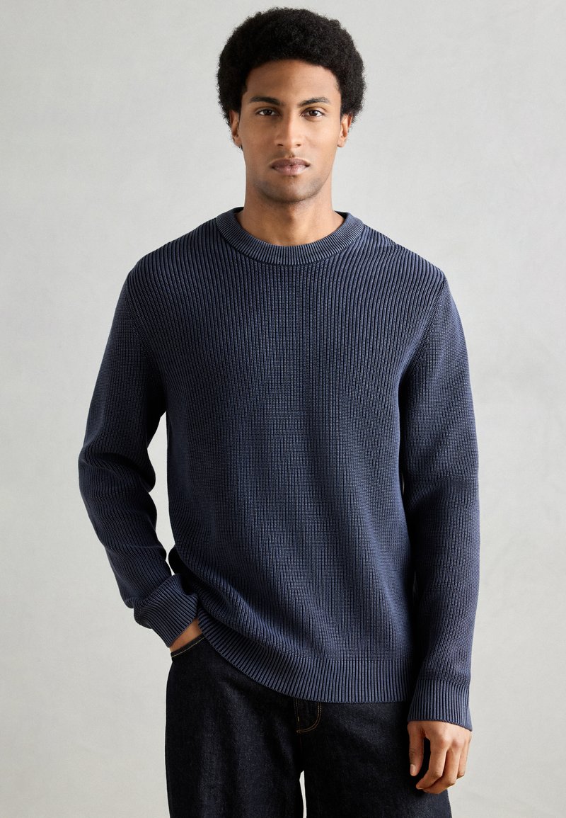 Camisola de malha azul-marinho com relevo canelado, decote redondo e mangas compridas. Textura canelada por toda a peça, corte descontraído e bainha ligeiramente curva.