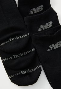 Chaussettes noires à la cheville en tissu extensible, dotées d'un logo "new balance" gris clair et d'un design épuré pour le confort.