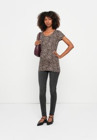 Top uzoraka leopard, napravljen od mekanog materijala, uparen sa sivim uskim trapericama i crnim štiklama. Dodaci uključuju bordo torbu na rame.