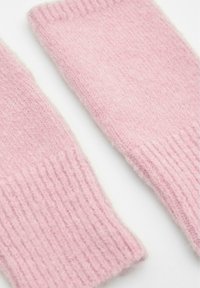 Mânuși de încheietură tricotate roz, realizate dintr-un material moale și pufos, cu textură ribbed și margini finisate. Prezintă un design simplu, fără cusături.