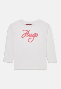 Hvit langermet t-skjorte laget av bomull, med rosa brodert "Hugo"-logo på fronten, rund halslinning og rett nederkant.