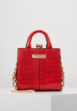 Kleine rote Handtasche mit Krokodil-Textur, goldener Kette, abgerundeten Griffen und goldenem Verschluss auf schlichtem Hintergrund.