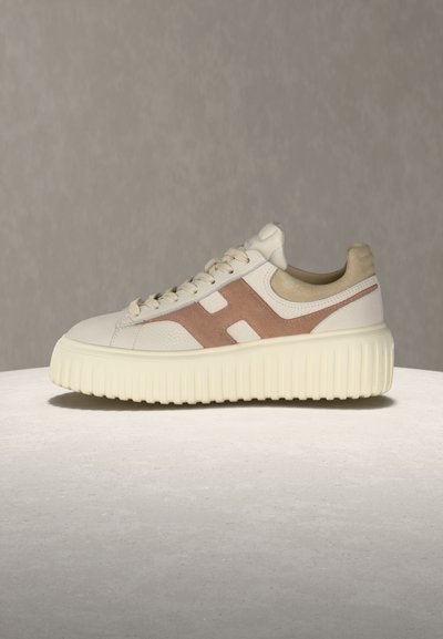 Λευκό και μπεζ αθλητικό παπούτσι με κορδόνια, με παχύ ραβδωτό πέλμα και μεγάλο καφέ σουέτ σχέδιο "H" στο πλάι.