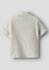 Kortärmad skjorta i en ljus gräddfärg med texturerad, ribbad tyg. Har en klassisk krage och subtila vertikala ränder.