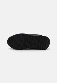 Zwarte sneakerzool met gestructureerd rubber voor grip. Bevat een loopvlakpatroon met horizontale en verticale lijnen en een logodetail.