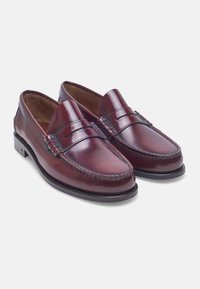 Bordeaux leren loafers met een gladde afwerking, gedetailleerde stiksels en een klassieke instapontwerp. Platte zool met minimale accenten.