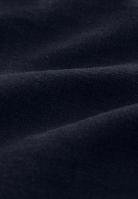 Tejido en un oscuro tono navy con una textura tejida, que muestra suaves pliegues y un leve brillo, ideal para prendas de vestir o tapicería.