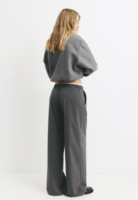Szara krótka bluza z szerokimi rękawami, w zestawieniu z ciemnoszarymi spodniami typu wide-leg z elastycznym paskiem i bocznymi kieszeniami.