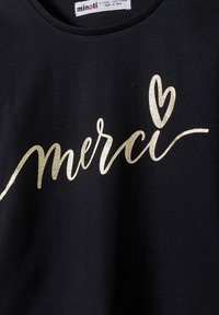 Crna majica s zlatnim sjajnim otiskom riječi "merci" i malim srcem kao akcentom. Izrađena od mekog pamučnog materijala.