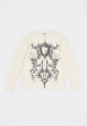 Kreminė ilgomis rankovėmis marškinėliai su juodu simetrišku abstrakčiu grafiku, primenančiu skydą su smaigaliais priekyje.