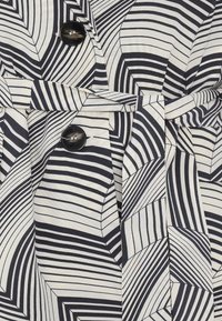 Vestito button-up con un motivo a foglia a righe bianche e nere, con dettaglio in vita legato e due bottoni rotondi neri.