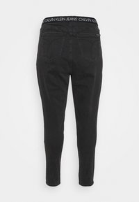 Úzké černé džíny s vysokým pasem a bílým brandingem "Calvin Klein Jeans", dvěma zadními kapsami a hladkou denimovou texturou.