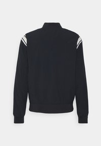 Giacca bomber nera con colletto alto, polsini e vita a coste. Presenta strisce bianche sulle spalle, una texture liscia e un fit regolare.