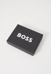 Black cardboard box featuring a white "BOSS" logo, rectangular shape, and smooth texture, with no additional patterns or accents.