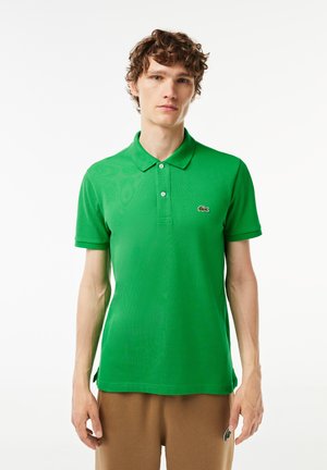 Grön polo skjorta i bomull, med klassisk krage, två knappar och en liten logotyp på vänster bröst. Mjuk och slät textur.